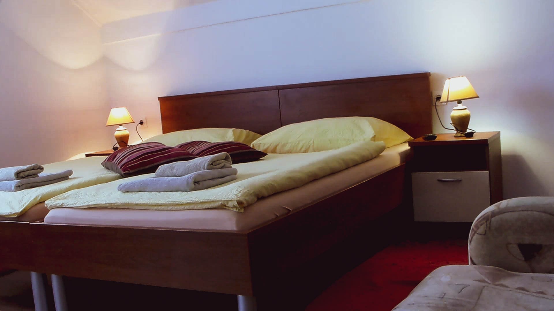 One king size bed, with two yellow pillows on it. It also has a yellow cover and red towels folded on the covers.